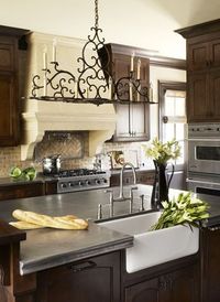 Kitchen with beautiful wood cabinets, plaster, stone look stove hood. Linda McDougald Design. Postcard from Paris Home